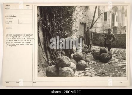 Eine Gruppe Amerikaner sieht neugierig zu, wie alte Munition, Steine für ein Katapult, im Innenhof eines restaurierten Schlosses in der Nähe des Moselkern ausgestellt wird. Das Foto wurde am 27. März 1919 von einer A.E.F. eng. Fotograf und mit Beschreibung erhalten am 11. April 1919. (111-SC-44903) Stockfoto