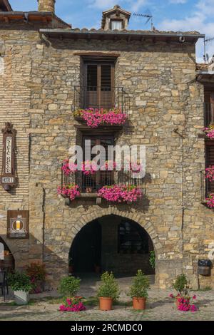 Altes Steinhaus mit wunderschönen Blumen am Fenster im mittelalterlichen Dorf Ainsa in den pyrenäen, Aragon, Spanien Stockfoto