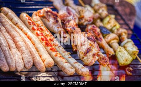 Grillgerichte mit verschiedenen Fleischsorten auf dem heißen Grillhähnchen, Würstchen und Spießen Stockfoto