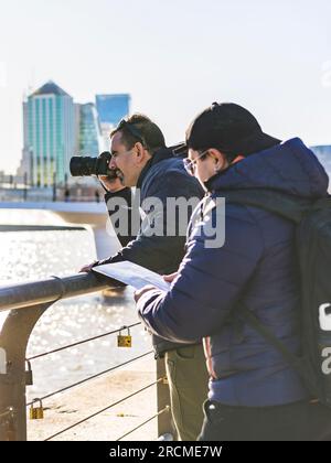 LGBT-Paare. Einer liest eine Karte, während der andere Fotos macht. Stockfoto