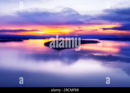 Farbenfroher Sonnenuntergang über der Insel Dangar auf dem ruhigen Spiegel der Seegasse Macquarie Pacific Ocean Lagune in Australien. Stockfoto