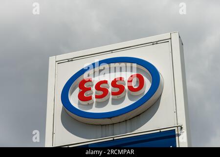 Esso-Logo der Tankstelle vor einem dramatischen dunklen Himmel. Die Marke ist Teil des Unternehmens ExxonMobil und im Energiesektor. Stockfoto