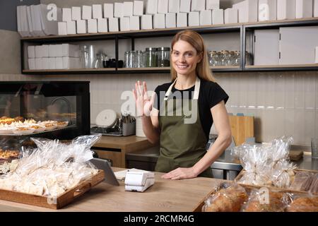 Glücklicher Verkäufer an der Kasse in der Bäckerei Stockfoto
