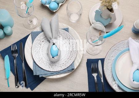 Festliche Tischgestaltung mit Hasenohren aus hellblauen Eiern und Servietten, Blick über den Tisch. Osterfeier Stockfoto