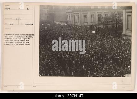 Soldaten, die dem Präsidenten Ebert treu sind, betreten das Regierungsgelände des Kanzlers in Berlin, Deutschland, unter Wachdienst. In der Wilhelmstraße treffen sie auf eine Menge Spartaker. Dieses Foto wurde am 6. Januar 1919 aufgenommen. Es ist Nummer 50737 in der Fotosammlung von amerikanischen Militäraktivitäten während des Ersten Weltkriegs. In der Beschreibung steht, dass die Soldaten von der Mafia der Spartaker begrüßt werden. Dieses Foto wurde mit dem Symbol „EA“ herausgegeben. Stockfoto