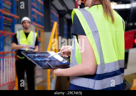 Junge, weiße Ingenieurin, die ein digitales Tablet benutzt, und ein Mann oder Arbeiter, der den Elektrozug für die Planung von Wartungsarbeiten in der Station, im Transport und in der Infrastruktur überprüft Stockfoto