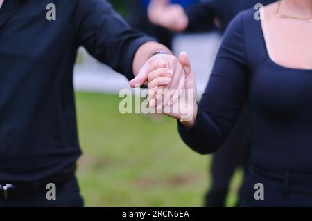 Junger Mann und Frau, die Händchen halten und gemeinsam auf einer Veranstaltung im Freien tanzen. Liebe, Zusammensein, Team und Hochzeitshintergrund. Stockfoto