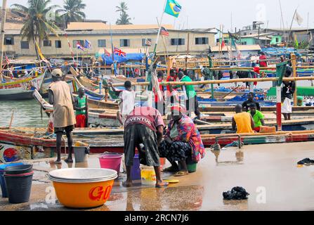 Fischerboote, die am Fischmarkt anlegen, während sich die Leute bereit machen, Fisch zu verkaufen, in Kapküste, Ghana, Westafrika, Stockfoto