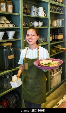Vietnamesische Kellnerin, die belgische Waffeln mit Salat in einem Café serviert Stockfoto