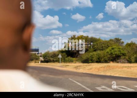 ein afrikanischer Mann, der eine Inspektionsdrohne mit Infrarot bedient, am Nachmittag in der Nähe der Straße Stockfoto