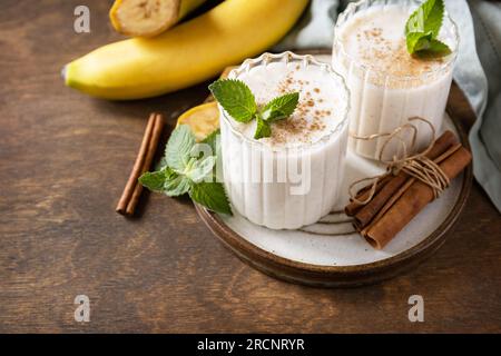 Bananen-Smoothie mit Zimt in Trinkglas auf Holzhintergrund. Entgiftungsmenü. Speicherplatz kopieren. Stockfoto