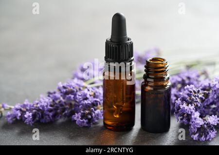 Zwei Flaschen ätherisches Aromatherapie-Öl mit violetten Lavendelblüten auf einem Tisch, mit Platz für Kopien Stockfoto