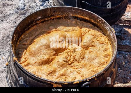 Afrikanische Küche im Freien, riesiger Topf mit Haferbrei in einem Gusseisentopf Stockfoto