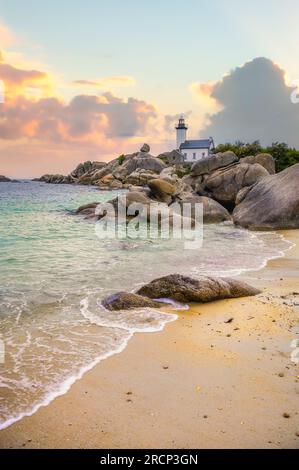 Der Leuchtturm von Pontusval, der sich an einem felsigen Punkt im Norden von Finistere in der Bretagne befindet, überblickt bei Sonnenaufgang ein Meer aus transparentem türkisfarbenem Wasser Stockfoto