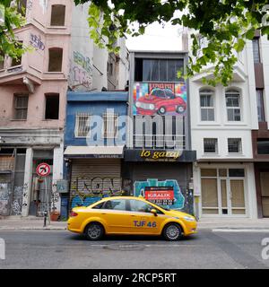 Gelbes Taxi auf einer Straße mit verschlossenen Geschäften im Stadtteil Karakoy von Istanbul mit einem Ed-Auto, das an der Wand eines Gebäudes abgebildet ist. Türkei Stockfoto