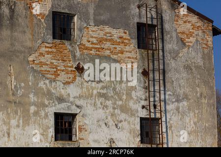 Außenansicht eines alten Backsteingebäudes mit verrosteten Feuerlöschern. Stockfoto