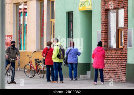 RUZOMBEROK, SLOWAKEI - 31. MÄRZ 2020: Menschen mit Gesichtsmasken vor dem Laden im Zentrum der Stadt Stockfoto