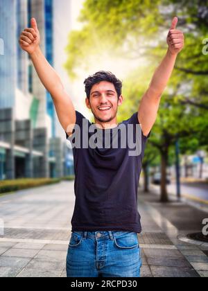 Kopf- und Schulterfoto eines gutaussehenden jungen Mannes mit grünen Augen, der lacht, in der Stadt, in die Kamera schaut, T-Shirt trägt Stockfoto