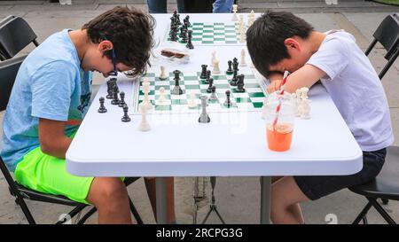 London, Großbritannien. 16. Juli 2023. Zwei Jungs scherzen während eines Spiels herum. Beim jährlichen ChessFest am Trafalgar Square können Spieler aller Altersstufen und Fähigkeiten ihre Schachfähigkeiten erneut gegen Mitspieler und mehrere Prominente ausprobieren. Das ChessFest ist das größte Schachspiel seiner Art in Großbritannien und kann für die Öffentlichkeit kostenlos besucht werden. Kredit: Imageplotter/Alamy Live News Stockfoto