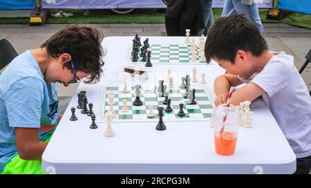 London, Großbritannien. 16. Juli 2023. Zwei Jungs scherzen während eines Spiels herum. Beim jährlichen ChessFest am Trafalgar Square können Spieler aller Altersstufen und Fähigkeiten ihre Schachfähigkeiten erneut gegen Mitspieler und mehrere Prominente ausprobieren. Das ChessFest ist das größte Schachspiel seiner Art in Großbritannien und kann für die Öffentlichkeit kostenlos besucht werden. Kredit: Imageplotter/Alamy Live News Stockfoto