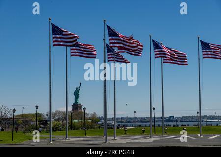 Jersey City, NJ, USA – Mai 2022; Blick über die Flag Plaza im Liberty State Park mit amerikanischen Flaggen im Wind und Blick auf die Freiheitsstatue gegen einen Cl Stockfoto