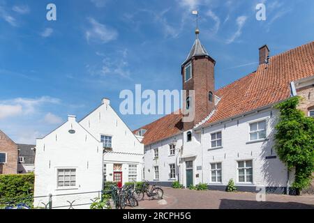 Amersfoort, Niederlande – Juni 2022; Vertikale Ansicht von weißen Ziegelgebäuden und Turm in der Muurhuizen Street (Wandhäuser); Häuser erbaut auf der Stockfoto