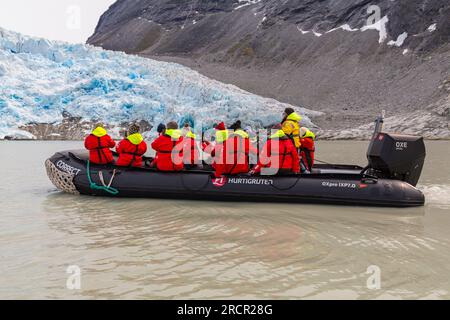 Touristen auf dem Zodiac können den Gletscher im Kvanefjord, Grönland, im Juli aus nächster Nähe betrachten Stockfoto