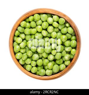 Frische grüne Erbsen in einer Holzschüssel. Rohe, kleine kugelförmige Samen der Hülsenfrucht Pisum sativum von grünlicher und gelblicher Farbe, hauptsächlich für Suppen verwendet. Stockfoto