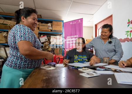 El Espino, La Libertad, El Salvador - Oktober 11 2022: Frauen, die sich zusammentun, um andere an einem Tisch zu bezahlen und Geld während eines Community Saving Group Meetin zu zählen Stockfoto