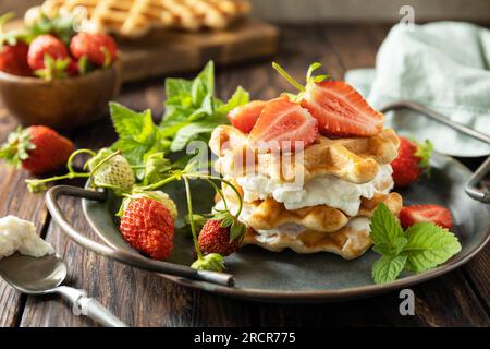 Hausgemachte belgische Waffeln mit frischen Berrie-Erdbeeren und Ricotta-Käse zum Frühstück auf einem rustikalen Tisch. Stockfoto