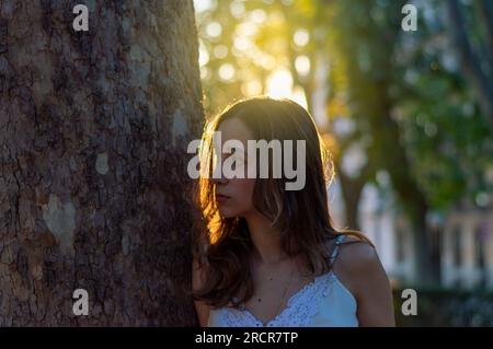 Horizontale Nahaufnahme einer hübschen jungen Frau, die neben einem Baum steht Stockfoto