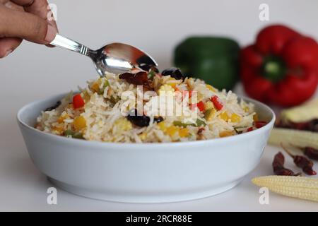 Kalter Knoblauchgemüse-Reis. Leicht gewürzter Basmati-Reis mit Knoblauchgeschmack, sautierter Paprika und Babymais. Aufnahme auf weißem Hintergrund zusammen mit r Stockfoto