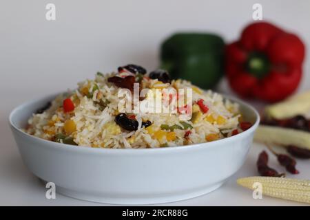 Kalter Knoblauchgemüse-Reis. Leicht gewürzter Basmati-Reis mit Knoblauchgeschmack, sautierter Paprika und Babymais. Aufnahme auf weißem Hintergrund zusammen mit r Stockfoto