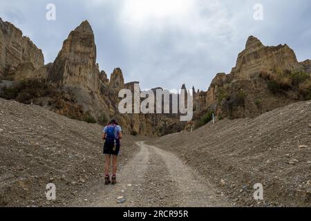 Palca, La Paz, Bolivien - 7 2022. August: Spaziergang einer jungen indigenen Frau auf einer Schotterstraße in den Bergen von Valle de Las Animas (Spirits' Valley) Stockfoto