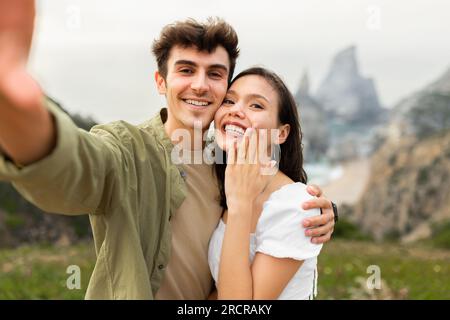 Ein unvergesslicher Vorschlag am Strand. Glückliches Paar, das nach der Verlobung ein Selfie macht Stockfoto