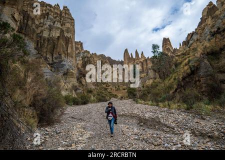 Palca, La Paz Bolivien - August 7 2022: Junge indigene Frau geht allein auf einem trockenen Flussbett in den Bergen von Valle de Las Animas (Spirits' Stockfoto