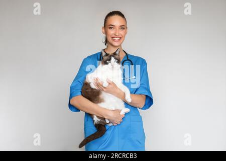 Glückliche Tierärztin Lady In Uniform, Haustier, Grauer Hintergrund Stockfoto