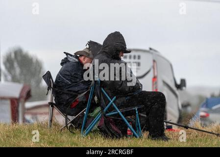 Fairford, Gloucestershire, Großbritannien. 16. Juli 2023. Flugbegeisterte, die die Royal International Air Tattoo Airshow anschauen, mussten sich während der Veranstaltung unter ein paar vorbeiziehenden Regenfällen verstecken Stockfoto