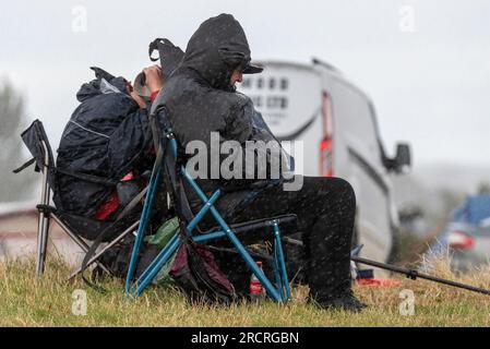 Fairford, Gloucestershire, Großbritannien. 16. Juli 2023. Flugbegeisterte, die die Royal International Air Tattoo Airshow anschauen, mussten sich während der Veranstaltung unter ein paar vorbeiziehenden Regenfällen verstecken Stockfoto