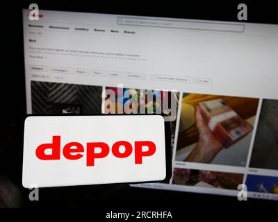 Person, die ein Mobiltelefon mit dem Logo des Social-E-Commerce-Unternehmens Depop Limited auf dem Bildschirm vor der Unternehmenswebseite hält. Konzentrieren Sie sich auf das Display des Telefons. Stockfoto