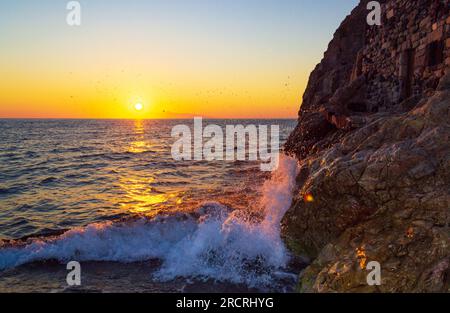 Sonnenaufgang über dem Ägäischen Meer und altes Höhlenhaus im Mesa Vouno an der Küste. Foto am Strand des Dorfes Kamari, Insel Santorin, Griechenland Stockfoto