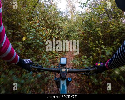 Fahren Sie mit einem Mountainbike-Lenker aus der Sicht des Fahrers in einem Wald auf einer einzigen Strecke Stockfoto