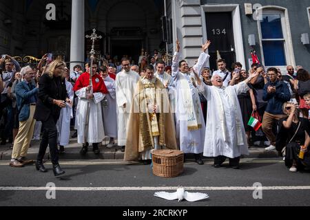 London, Großbritannien. 16. Juli 2023 Priester lassen Tauben vor der italienischen Kirche St. Peter frei, aber eine Taube fliegt nicht, vor der Prozession unserer Lieben Frau von Mount Carmel, beginnend bei der italienischen Kirche St. Peter und dann um die Straßen von Clerkenwell. Die Schwimmwesten zeigen lebensgroße Darstellungen biblischer Szenen in einem römisch-katholischen Festival, das seit den 1880er Jahren jährlich in der Gegend stattfindet, die einst das kleine Italien der Hauptstadt war. Kredit: Stephen Chung / Alamy Live News Stockfoto