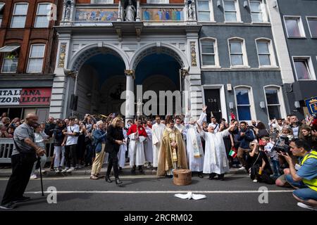 London, Großbritannien. 16. Juli 2023 Priester lassen Tauben vor der italienischen Kirche St. Peter frei, aber eine Taube fliegt nicht, vor der Prozession unserer Lieben Frau von Mount Carmel, beginnend bei der italienischen Kirche St. Peter und dann um die Straßen von Clerkenwell. Die Schwimmwesten zeigen lebensgroße Darstellungen biblischer Szenen in einem römisch-katholischen Festival, das seit den 1880er Jahren jährlich in der Gegend stattfindet, die einst das kleine Italien der Hauptstadt war. Kredit: Stephen Chung / Alamy Live News Stockfoto