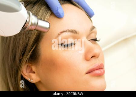 Frau, die sich einer Laserentfernung unterzieht, permanentes Make-up. Kosmetiker entfernt Tattoo-Augenbraue im Schönheitssalon. Stockfoto