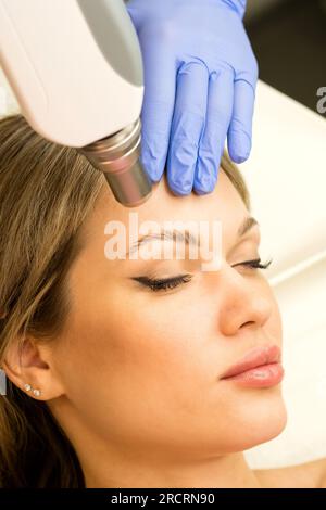 Frau, die sich einer Laserentfernung unterzieht, permanentes Make-up. Der Schönheitssalon entfernt die Tattoo-Augenbraue. Stockfoto