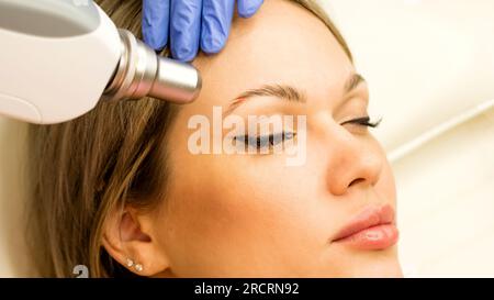 Frau, die sich einer Laserentfernung unterzieht, permanentes Make-up. Der Schönheitssalon entfernt die Tattoo-Augenbraue. Stockfoto