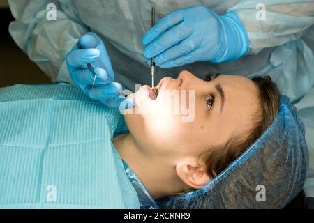 Der Zahnchirurg untersucht den Mund der Patientin, bevor er Weisheitszahn, den Oberkiefer-Drittmolar, entfernt. Echte Prozedur Stockfoto