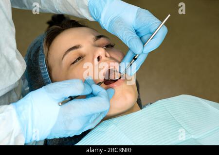 Der Zahnchirurg untersucht den Mund der Patientin, bevor er Weisheitszahn, den Oberkiefer-Drittmolar, entfernt. Echte Prozedur Stockfoto