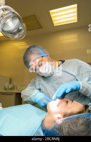 Der Zahnchirurg untersucht den Mund des Patienten, bevor er Weisheitszahn, den Oberkiefer-Drittmolar, entfernt. Echte Prozedur Stockfoto